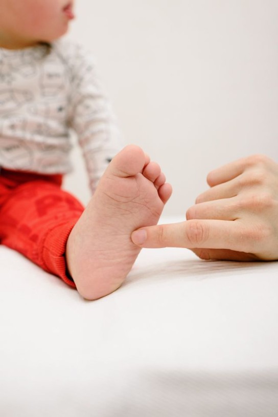 persoon raakt de voet van een baby aan (vergroot foto)
