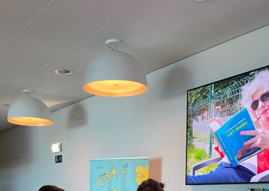 Twee vrouwen aan tafel met laptop en folders, promotie voor UiTPAS in Refter OostCampus. (vergroot foto)